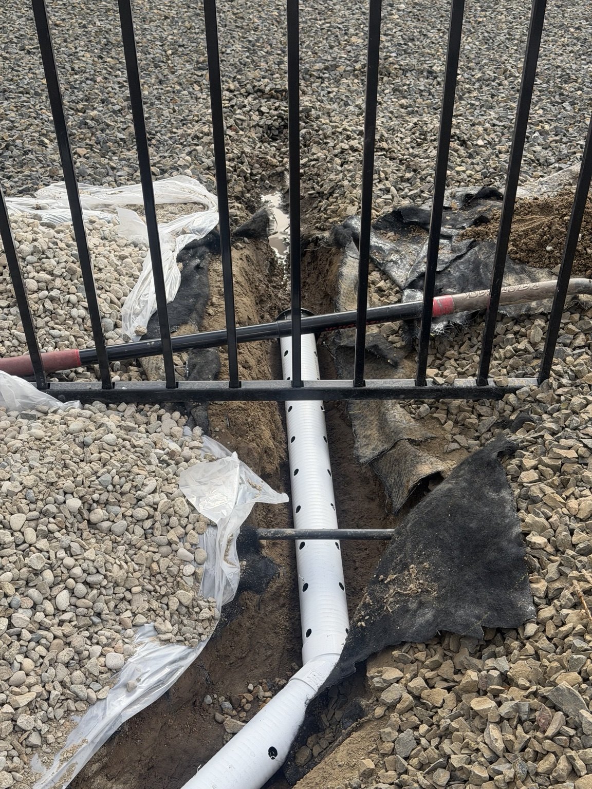 Drain pipe continuing beneath a metal fence